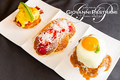 Sampler plate with an eggs benedict, mini stack of pancakes with strawberries, and loco moco topped with a sunny side up egg.