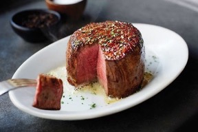 Filet mignon with a slice cut out to reveal a perfectly pink center.