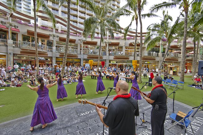 Row of female hula dancers performing for a crowd at Waikiki Beach Walk.