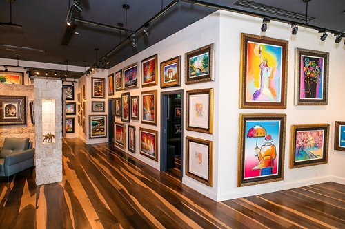 Interior gallery walls filled with various colorful paintings at Park West Hawaii in Waikiki Beach Walk.