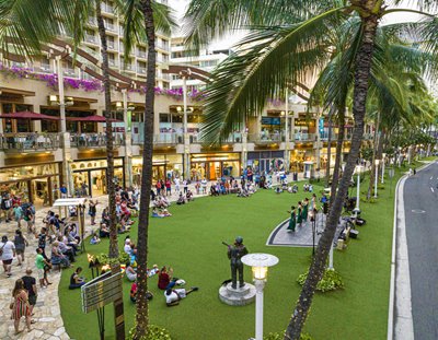 Cultural performance in Waikiki with Waikiki Beach Walk shops and restaurants in view