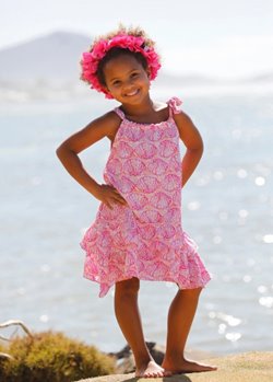 Young girl wearing a pink dress with seashell pattern to show Hawaiian kids fashion in Waikiki