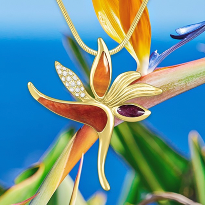 Pendant in the shape of a bird of paradise flower hanging in front of a real bird of paradise