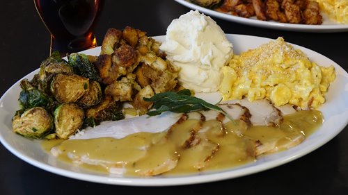 Yard House Thanksgiving plate with sliced turkey covered in gravy, Brussels sprouts, mashed potatoes and mac and cheese