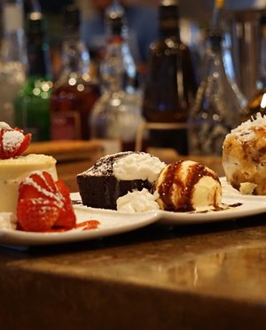 Strawberry cheesecake, fudge brownie sundae, & haupia bread pudding plated on a counter