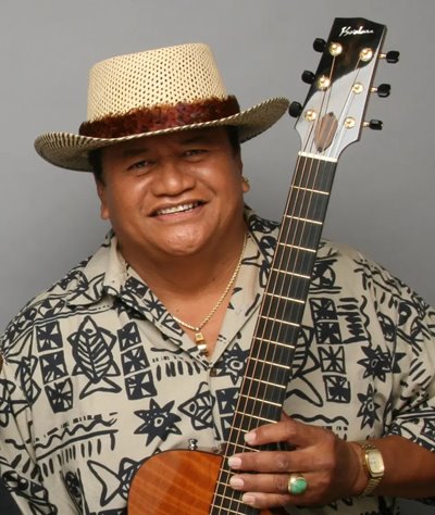 Ledward Kaapana wearing an aloha shirt & holding a guitar