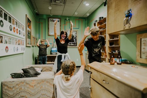 Mother & 3 kids with their hands up in celebration while playing an escape room game at Breakout Waikiki
