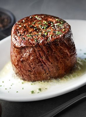 Cooked 8 oz filet steak on a sizzling white plate & topped with garnish from Ruth's Chris Steak House Waikiki.