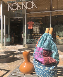 Blue & pink multi-print tapa pattern bag next to Hawaiian instruments in front of Noa Noa Waikiki's shop