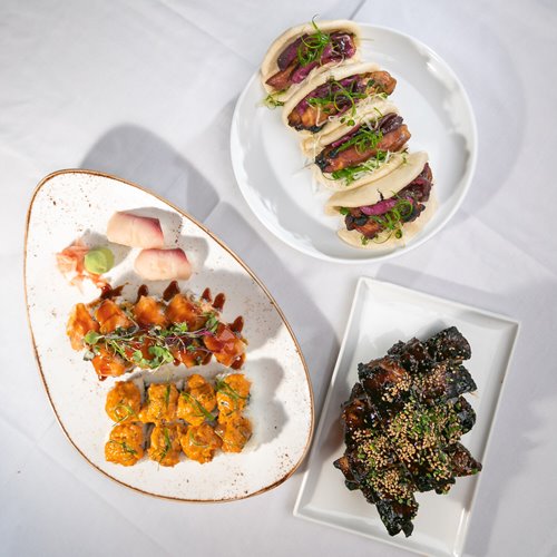 Overhead shot of Roy's Waikiki 3 Platter Pack featuring assorted nigiri sushi, szechuan baby back ribs, & kalbi chicken bao buns