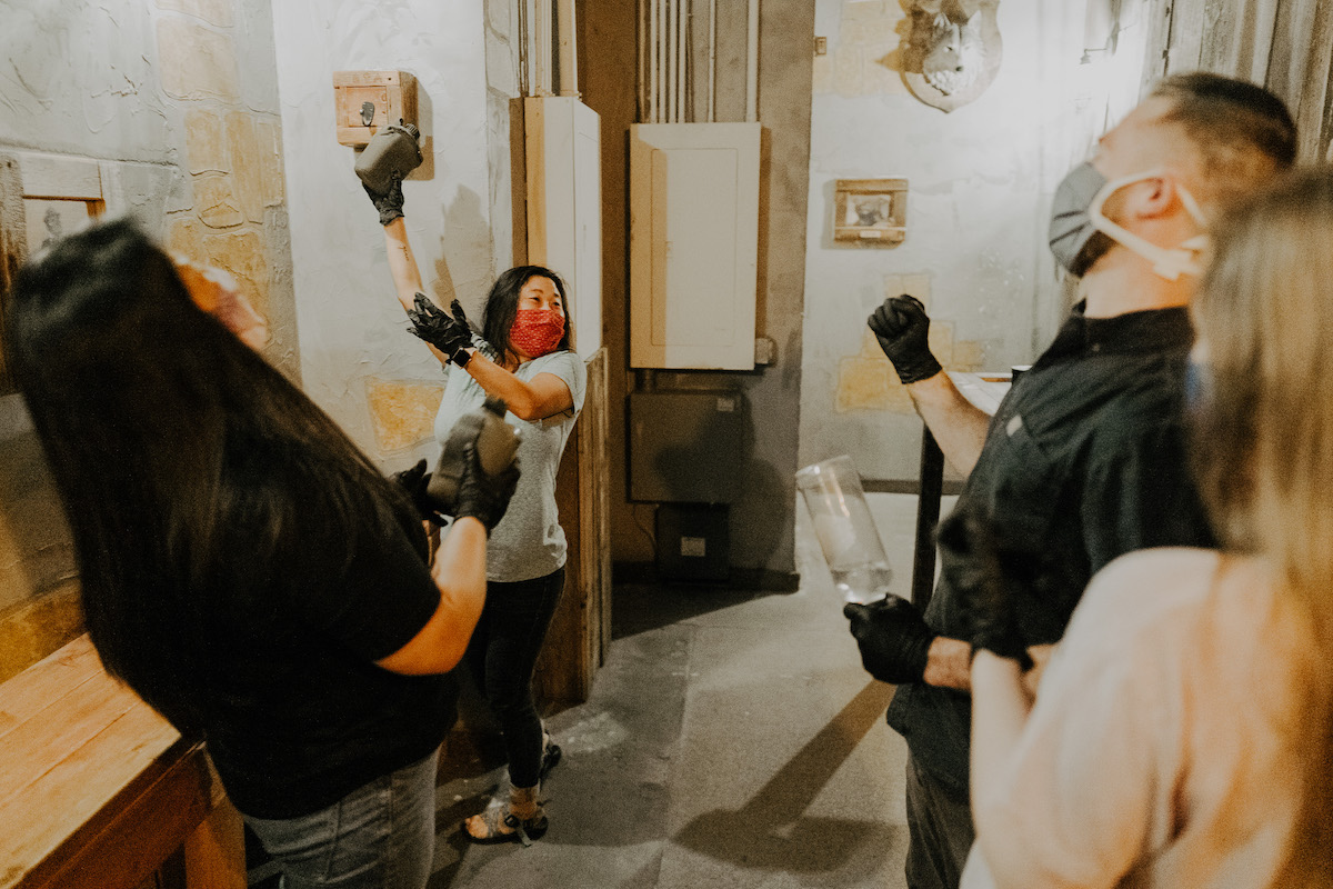 Group of 4 playing an escape room game while wearing masks and gloves