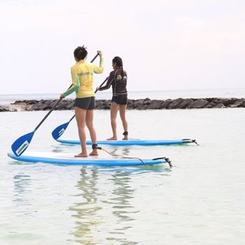 2 girls standing on SUP boards holding paddles on the water