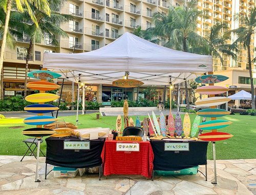Farmers market booth with custom, multicolored mini surfboards.