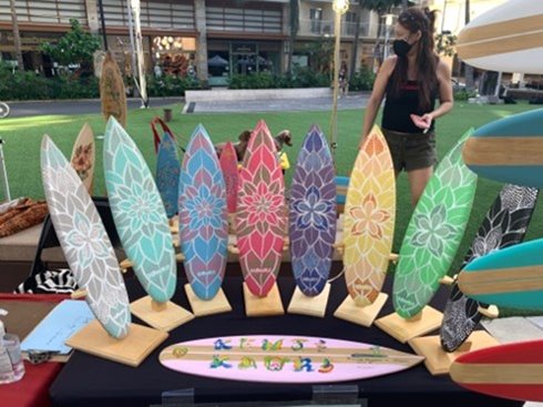 Colorful mini surfboards with painted floral designs at Waikiki Beach Walk's farmers market