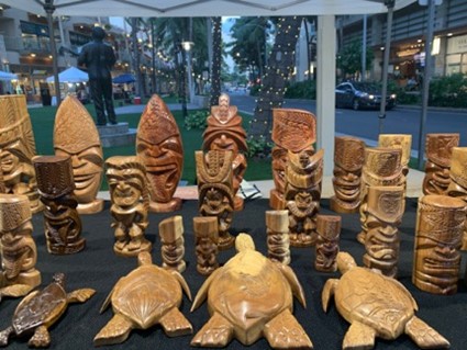 Variety of tiki statues & sea turtles carved out of wood.