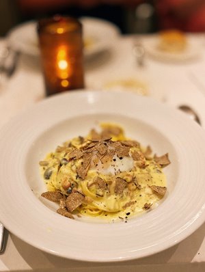 Plate of carbonara pasta topped with a poached egg & shaved truffles from Taormina Sicilian Cuisine in Waikiki.