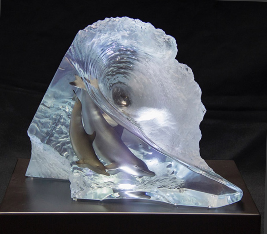 A sculpture of 3 dolphins swimming in a clear wave.