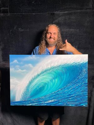 Chris Sebo holding a piece of his art depicting the barrel of a wave while showing a shaka.