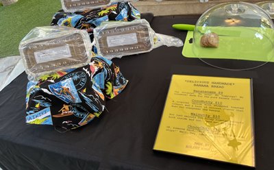 Two packaged banana bread tins alongside a yellow menu & green cutting board