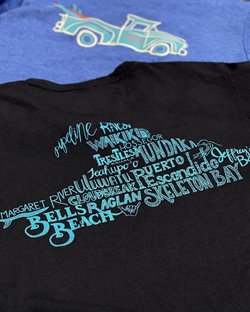 Close up of the back of a black shirt, which shows the names of different surf locations in blue arranged into the shape of a wave.