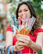 Woman holding an assortment of colorful chopsticks.