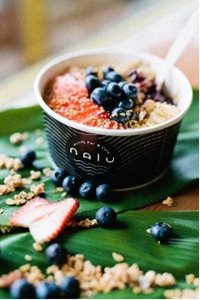 Acai bowl with fruit toppings in a black Nalu Health Bar & Cafe bowl