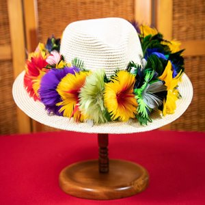 White woven hat with a lei of colorful feathers & tropical flowers wrapped around it.