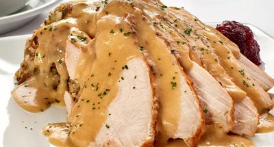 Slices of turkey covered in gravy on a plate