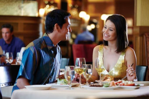 Man & woman smiling at each other while eating in a Waikiki restaurant