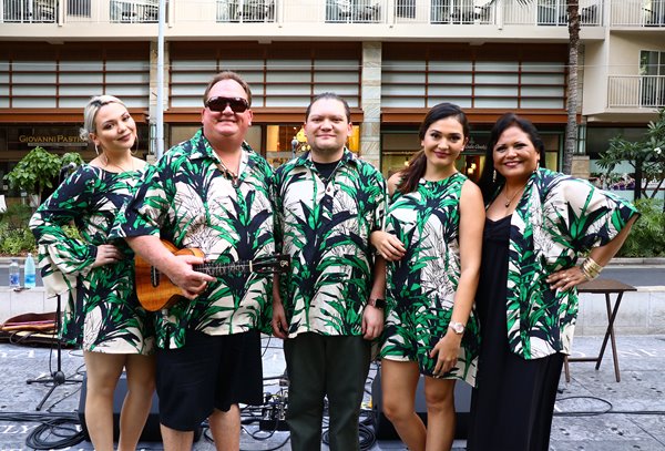 The musical group Kapena wearing matching green aloha attire & posing at the Plaza Stage.