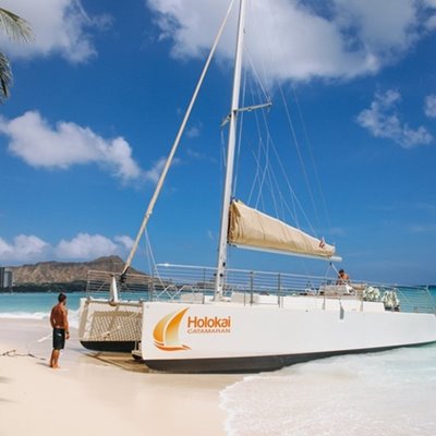 Catamaran marked "Holokai" docked on the sand with Diamond Head in the background.
