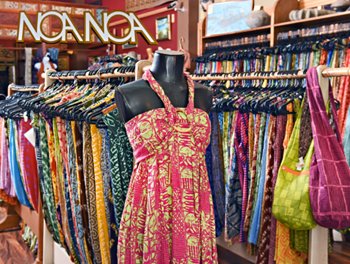 A colorful dress is showcased in a store filled with various vibrant clothing items.