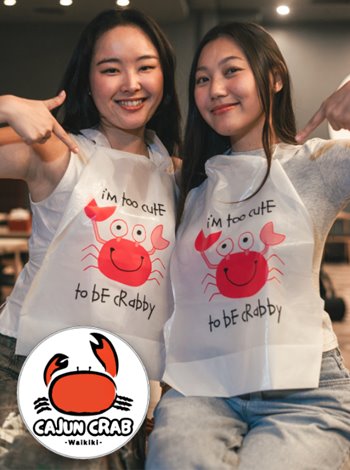 Two women wearing disposable crab-themed bibs, smiling and ready to enjoy a seafood meal together.